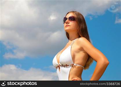 Girl in sunglasses in swimsuit against sky