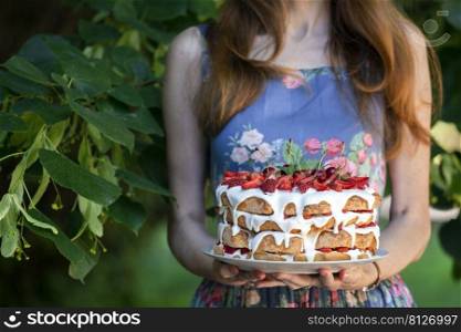girl in the garden holding a biscuit cake with cherries and strawberries 