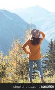 girl in the hat stands on the background of mountains