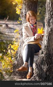girl in the park holding yellow maple leaves