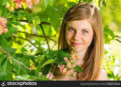 Girl in the sunshine smelling tree blossom in springtime