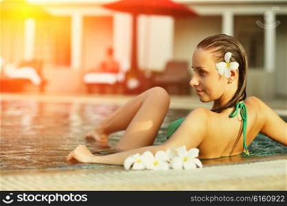 Girl in tropical swimming pool with flower in hairs