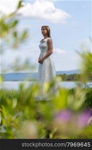 girl in white dress on the lake in the green against the sky