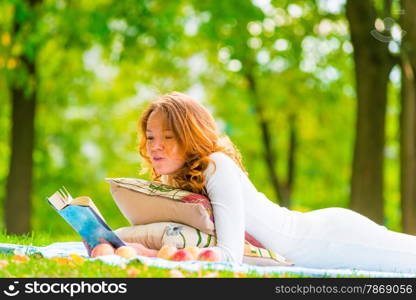 girl in white dress reading a book in the park