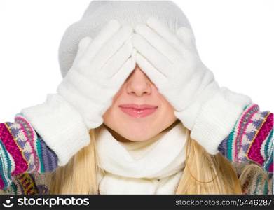 Girl in winter clothes covering eyes with hands