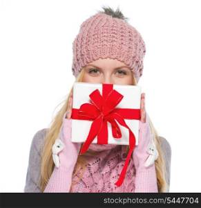Girl in winter clothes hiding behind christmas presenting box