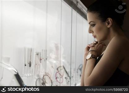 girl inside a shop , in ambient natural light looking some jewelery ,
