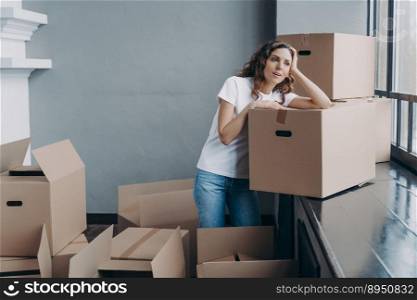 Girl is dreaming while sitting on floor in new apartment. Young woman enjoying view looking at the window. Happy attractive hispanic woman unpacking boxes. Concept of future and perspective.. Woman unpacking boxes and dreaming. Enjoying view looking at the window in new apartment.