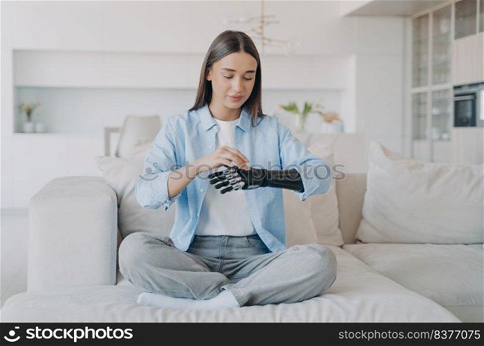 Girl is pressing buttons of electronic prosthesis. Disabled european woman is changing settings of bionic arm. Cyber sensor hand has processor chip. Artificial carbon limb. Scandinavian home interior.. Girl is pressing buttons of electronic prosthesis. Cyber sensor hand, artificial carbon limb.