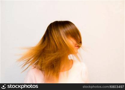 Girl is rotating Red Hair. Closeup young beautiful girl with red hair flying against white background