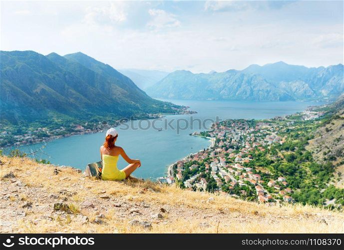 Girl is sitting on the mountain infront of the sea