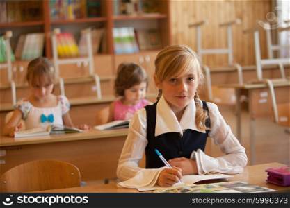 Girl is studying in classrom at the desk. Girl is studying