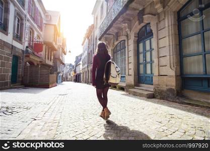 girl is walking along an empty street in the old town Morlaix. France