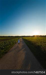 Girl is walking with a beagle dog on a leash in the sunset to the forest in rural area. Vertical photo. Girl is walking with a beagle dog on a leash in the sunset to the forest in rural area.