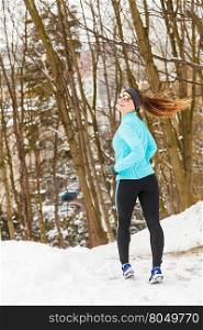 Girl jogging in frozen park, running among snow and trees, health fitness nature fashion concept.