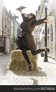 Girl jump on a street. Brown jacket.