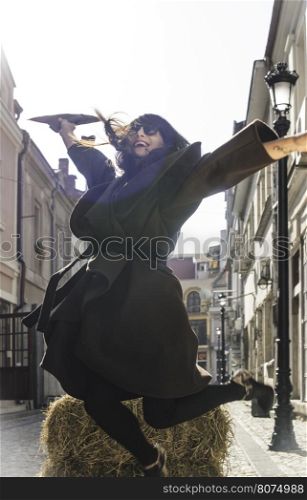 Girl jump on a street. Brown jacket.