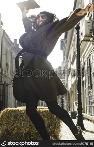 Girl jump on a street. Brown jacket.