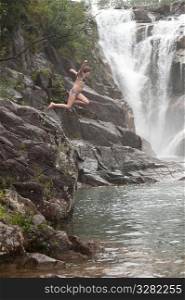 Girl jumping from cliff at Mountain Pine Ridge Reserve, Waterfall
