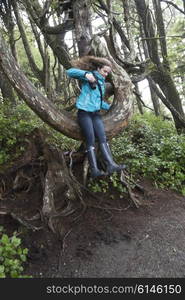 Girl jumping from tree, Wild Pacific Trail, Ucluelet, Pacific Rim National Park Reserve, Vancouver Island, British Columbia, Canada