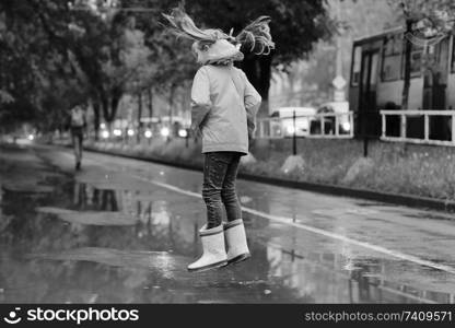 girl jumping in the puddles in the autumn rain