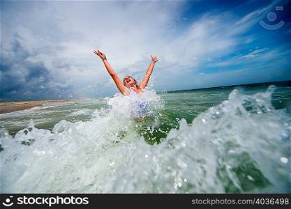 Girl jumping with joy in ocean wave