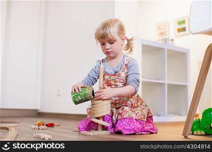 Girl kneeling on wooden floor playing with toys