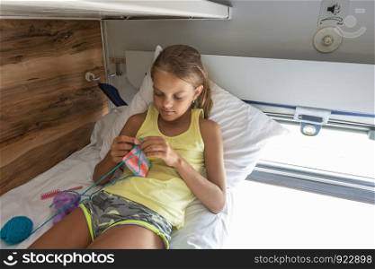 Girl knitting on the top shelf of a reserved seat car