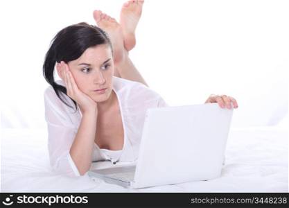 Girl laid on a bed with laptop