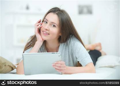 Girl laid on bed using notepad computer