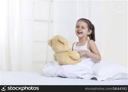 Girl laughing while playing with teddy bear