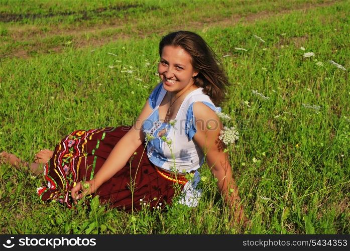 Girl lay in grass and laugh. She is smiling to you, and wind blows about her hairs.