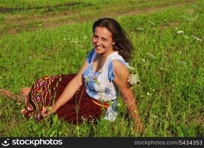 Girl lay in grass and laugh. She is smiling to you, and wind blows about her hairs.