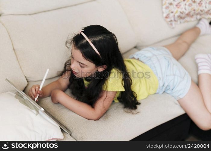 girl laying couch drawing tablet