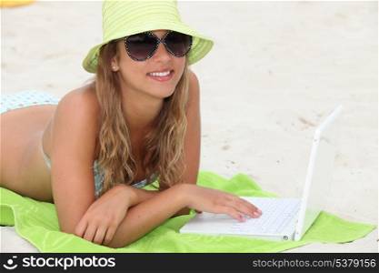 Girl laying on beach with laptop