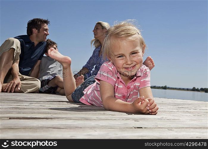 Girl laying on dock with family