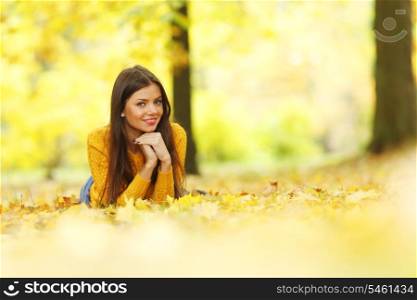 Girl laying on leafs in the autumn park