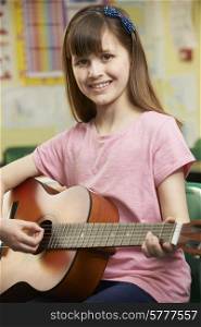 Girl Learning To Play Guitar In School Music Lesson