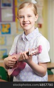 Girl Learning To Play Ukulele In School Music Lesson