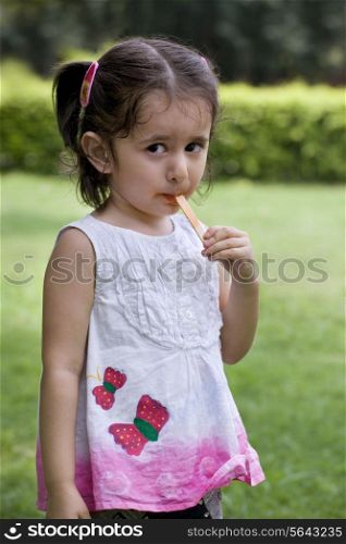 Girl licking stick in park