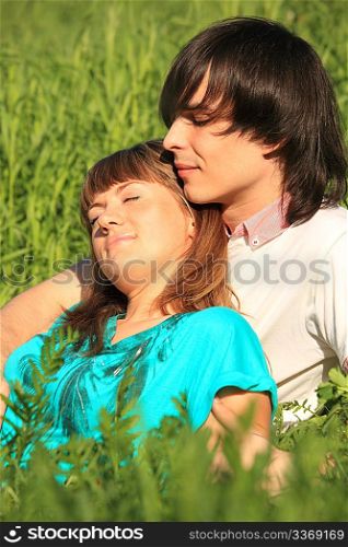 girl lies on guy sitting in grass