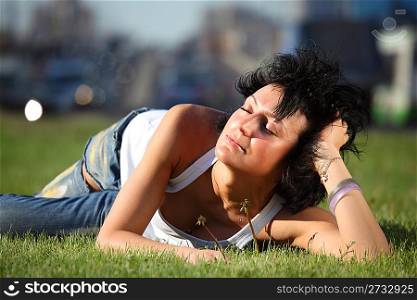 girl lies on lawn at road in city