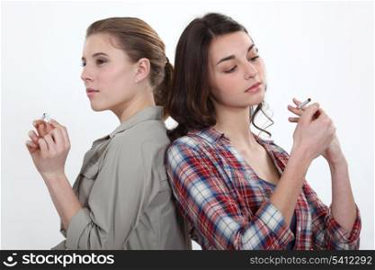 Girl lighting a cigarette as another snaps one in half