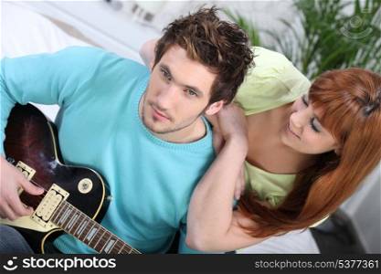 girl listening to man playing guitar