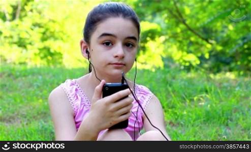 Girl listening to music on a smartphone in a park