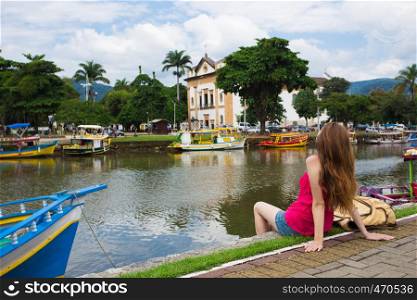 girl looking a the Paraty bay sitting on a quay