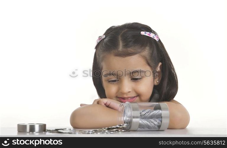 Girl looking at Indian coins spilled on table against white background