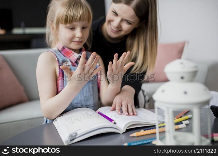 girl looking hands while doing homework with mom