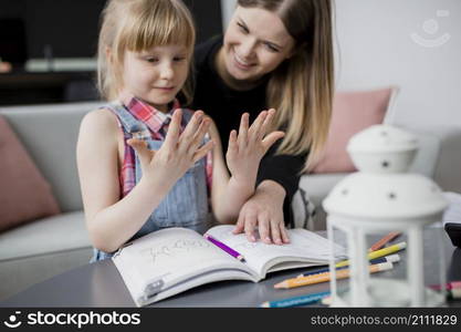 girl looking hands while doing homework with mom