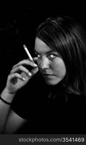 Girl looking into the camera holdig a cigarette. Black and white